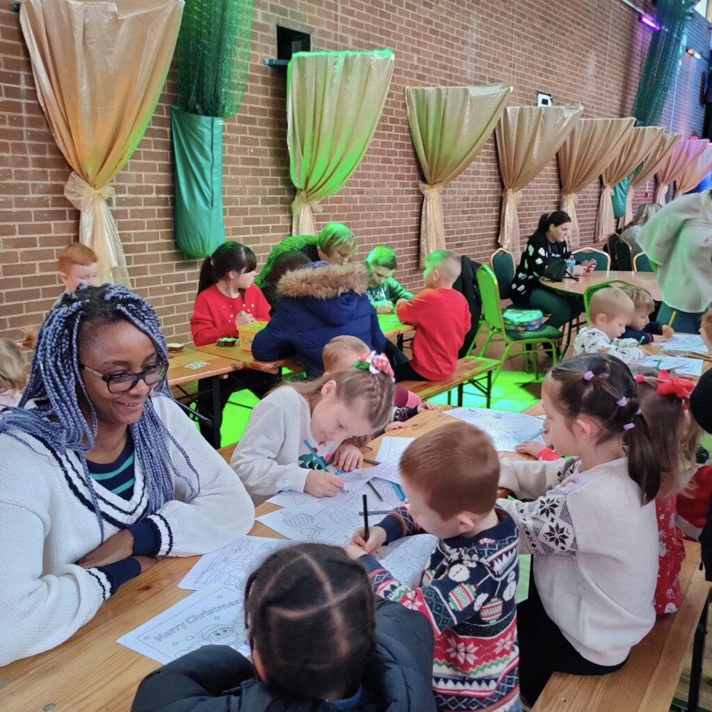 A volunteer at The Hunslet Club helping young people with their Christmas drawings