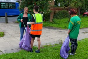 Three volunteers picking up litter on a path and patch of grass in Hunslet