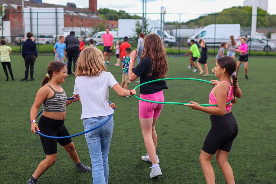 A group of girls playing with hula hoops at The Hunslet Club Activity Camp 