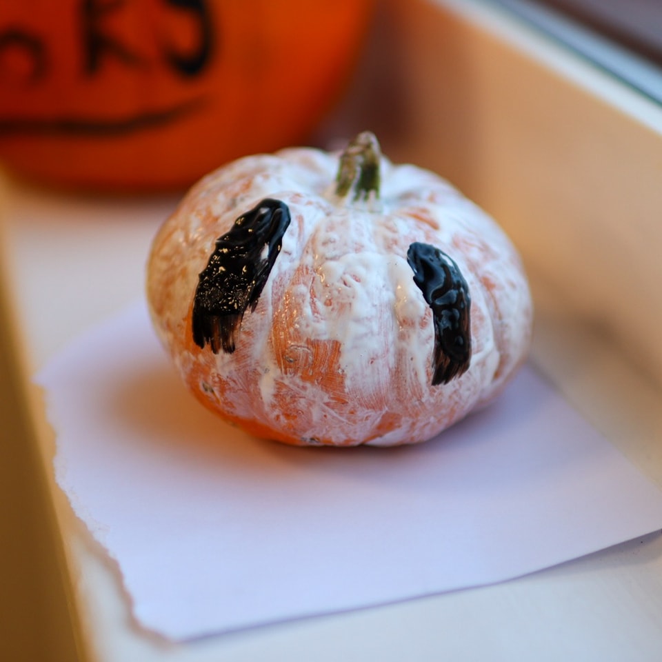 A tiny pumpkin on a shelf - painting white with long black eyes. 