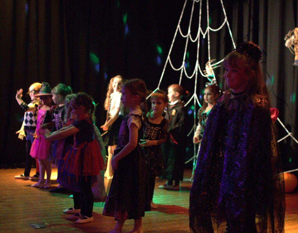 Young people dressed in different Halloween costumes standing on a stage. 